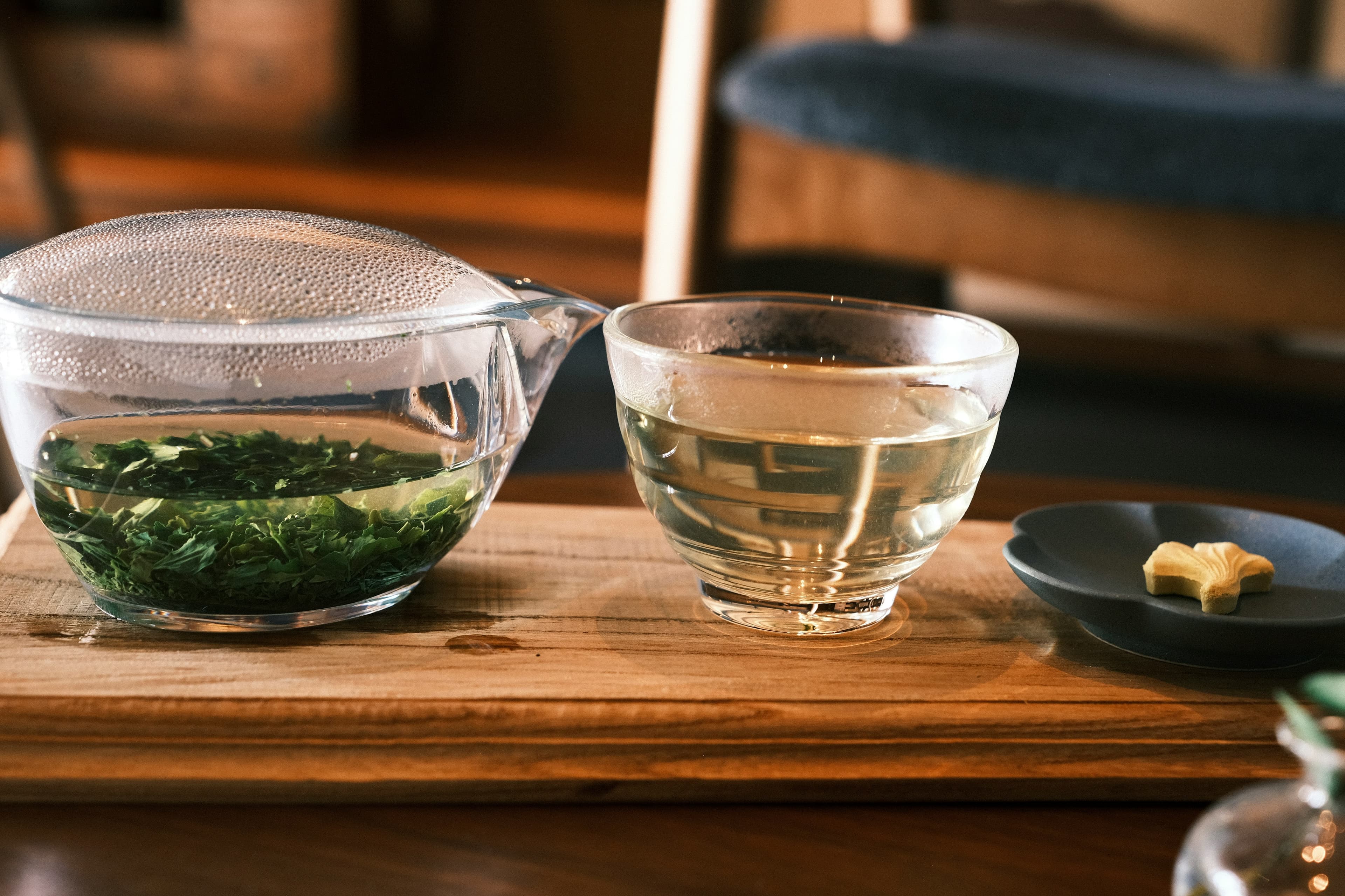 Green tea brewed in a glass pot with cups on a wooden tray (illustrative image)