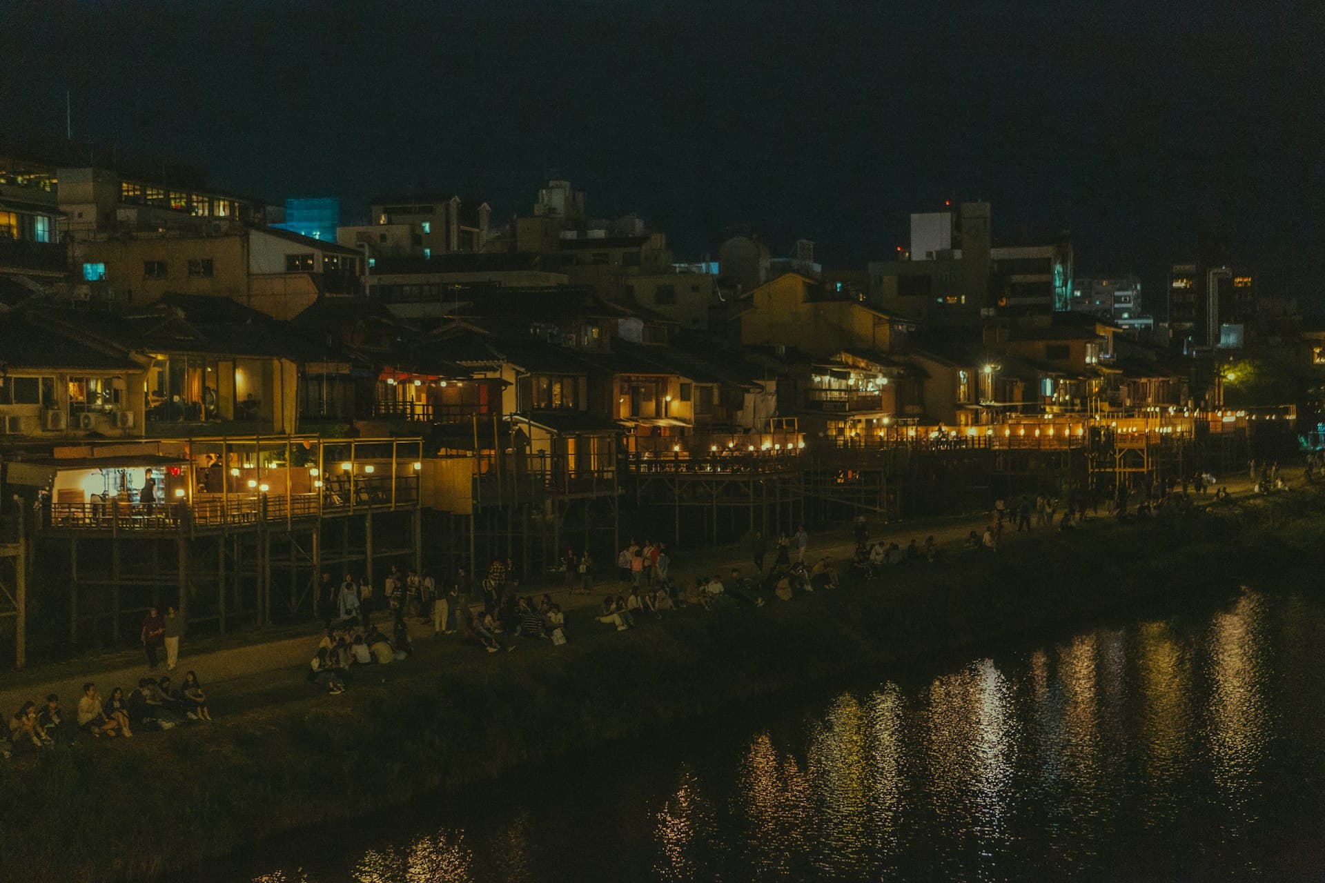 Lit kawayuka platforms and people gathering along the Kamogawa River at night (illustrative image)