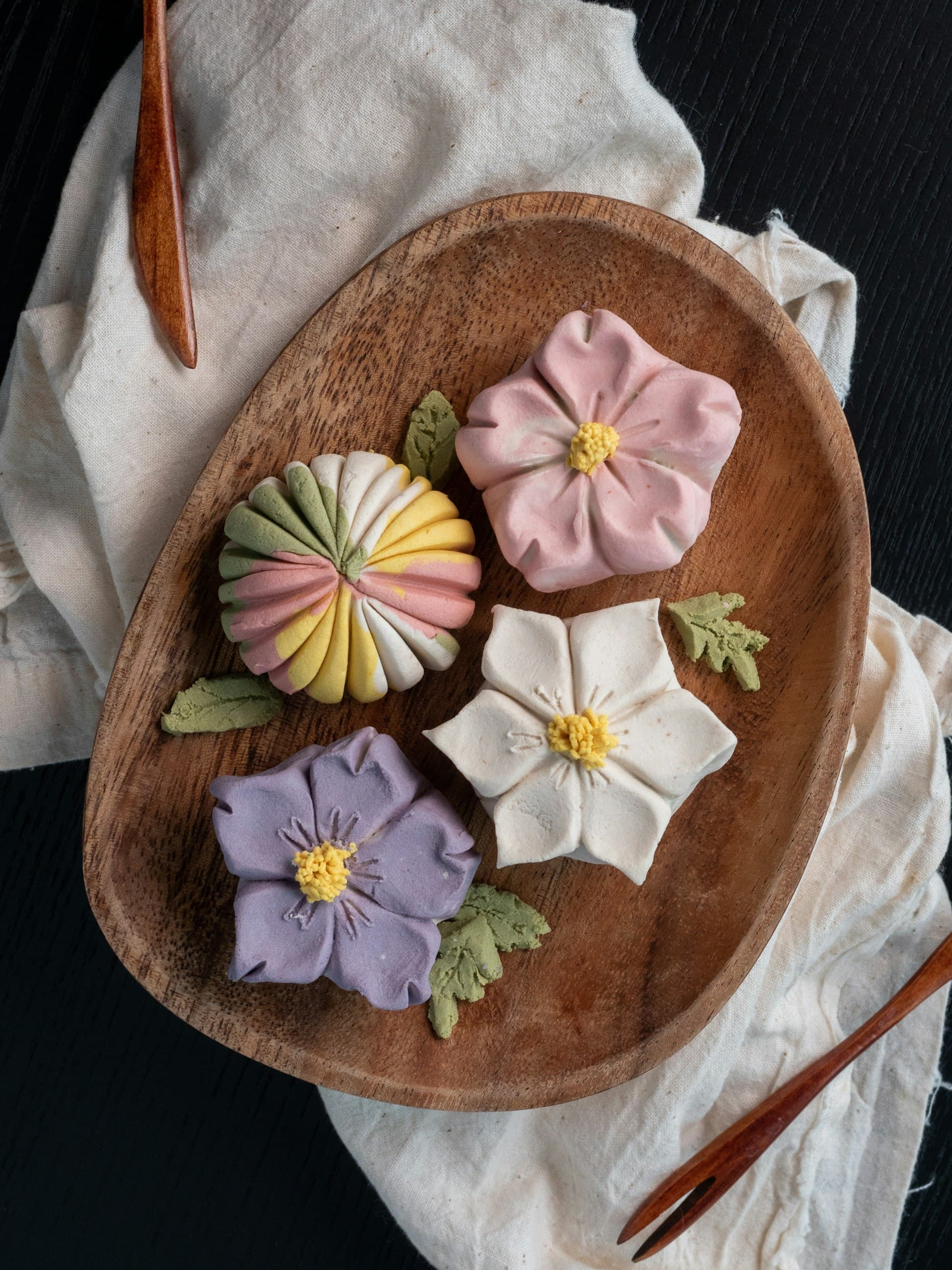 Flower-shaped namagashi sweets arranged on a wooden plate (illustrative image)