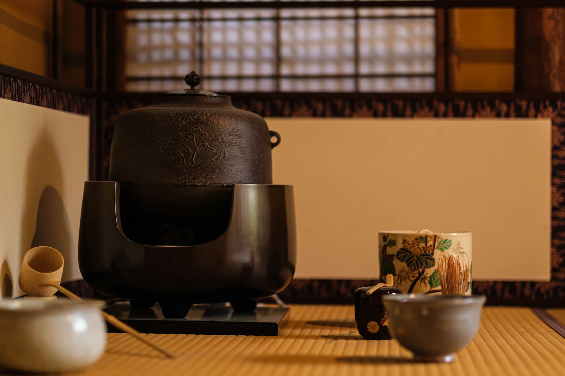 A tatami-floored tea room with an iron kettle and tea bowls arranged for tea (illustrative image)