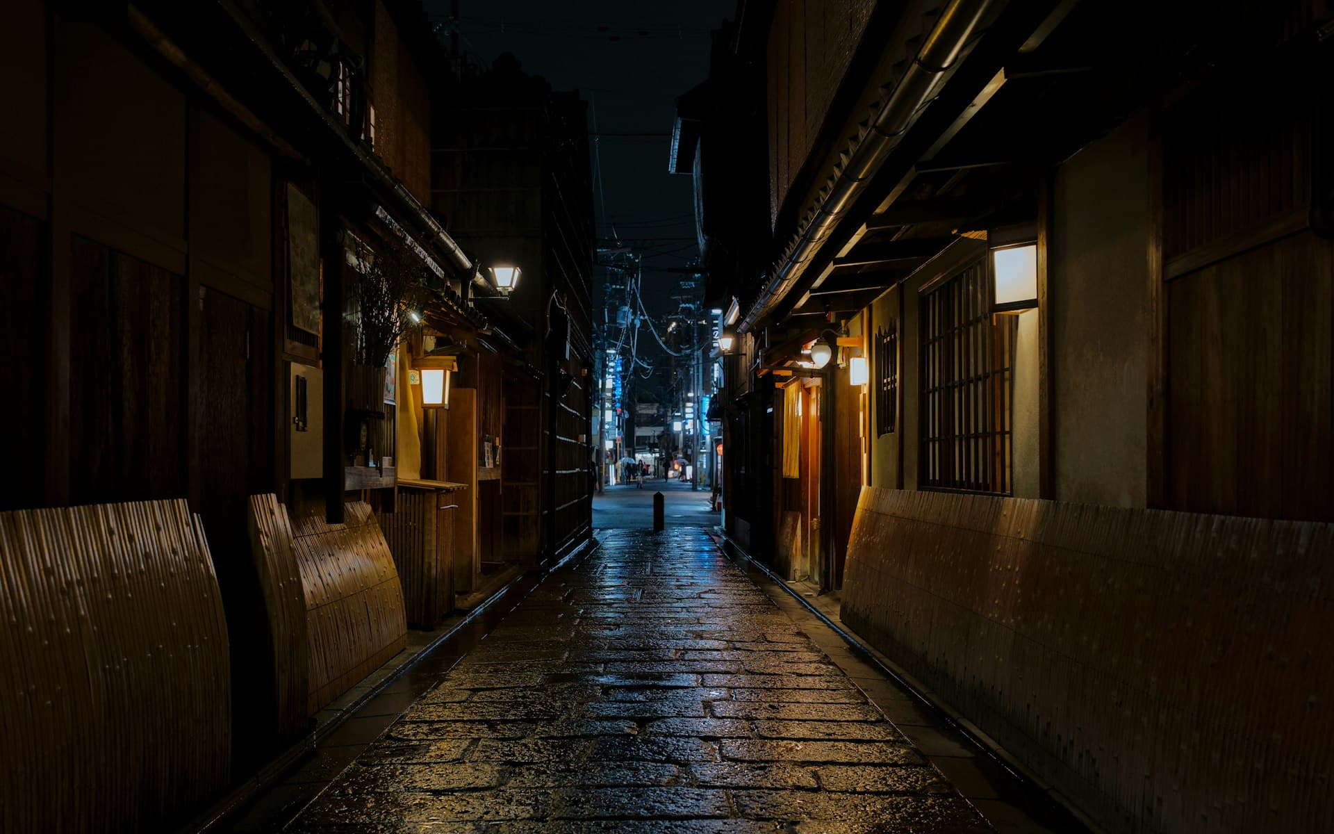 A rain-glistened stone-paved alley in Kyoto at night, lit by traditional lanterns (illustrative image)